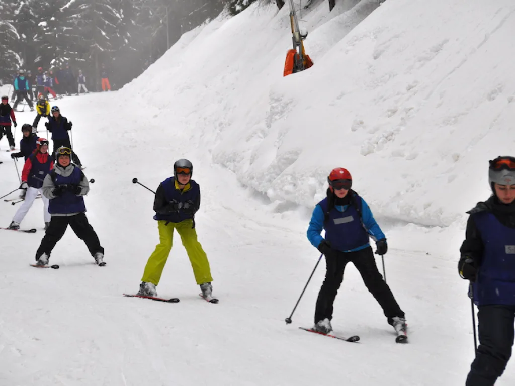 Mehrere Skifahrende auf dem Hang unter der Liftstütze.